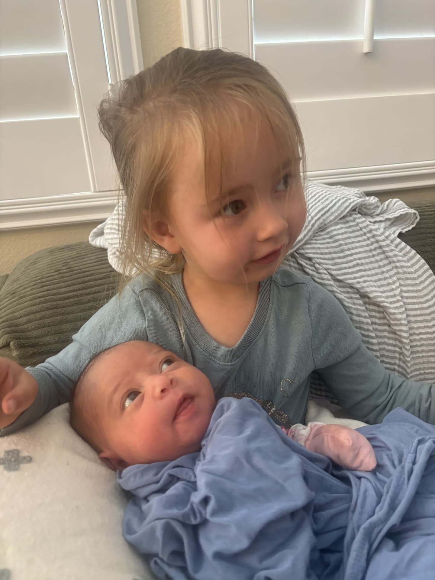 A young child sitting with a newborn baby at home