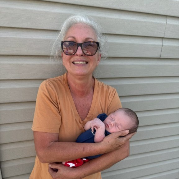 Brian's wife holding their newborn grandchild